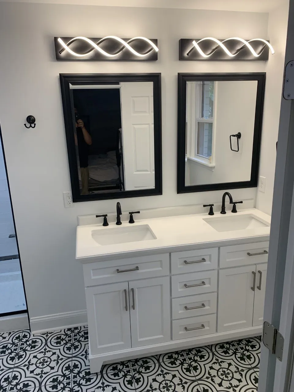 Modern bathroom with double vanity, black and white tile floor, and stylish lighting