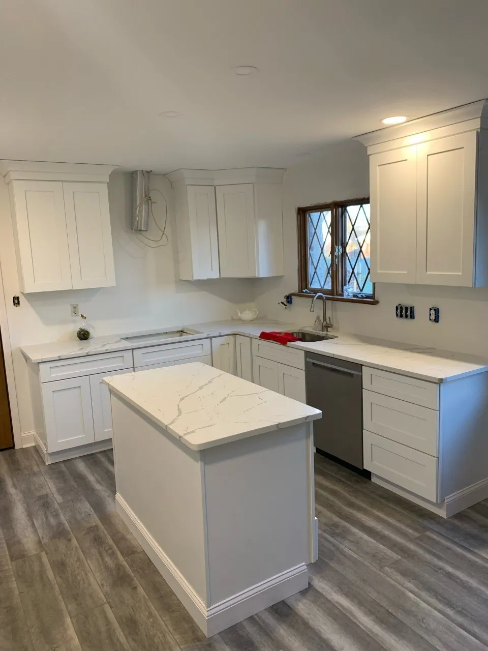 Modern kitchen with white cabinets, quartz countertops, and hardwood floors